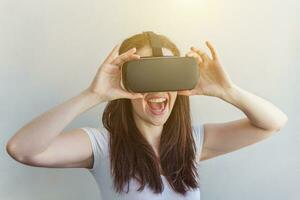 Smile young woman wearing using virtual reality VR glasses helmet headset on white background. Smartphone using with virtual reality goggles. Technology, simulation, hi-tech, videogame concept. photo