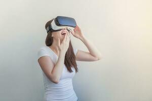 Smile young woman wearing using virtual reality VR glasses helmet headset on white background. Smartphone using with virtual reality goggles. Technology, simulation, hi-tech, videogame concept. photo