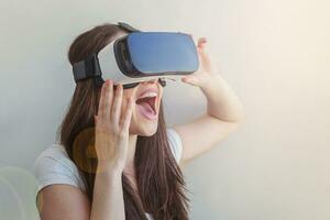 Smile young woman wearing using virtual reality VR glasses helmet headset on white background. Smartphone using with virtual reality goggles. Technology, simulation, hi-tech, videogame concept. photo