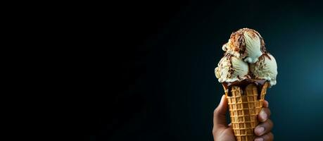 Hand holding vanilla ice cream cone on dark background photo