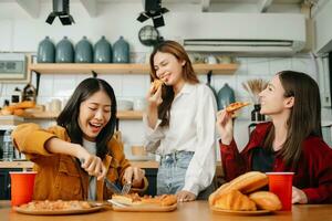 Group of friends making fun at home party.They sitting on desk in living room and eating pizza. happy photo