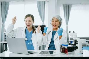 Medical team having a meeting with doctors in white lab coats and surgical scrubs seated at a table discussing a patients working online using computers in the medical industry photo