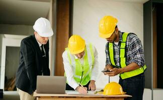 Two colleagues discussing data working and tablet, laptop with on on architectural project at construction site at desk in office photo