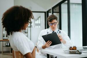 médico y paciente discutiendo algo mientras están sentados en la mesa. concepto de medicina y atención de la salud. foto