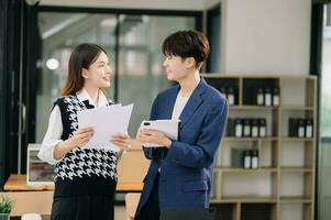 Two Asian business workers talking on the smartphone and using laptop at the modern office. photo