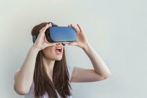 Smile young woman wearing using virtual reality VR glasses helmet headset on white background. Smartphone using with virtual reality goggles. Technology, simulation, hi-tech, videogame concept. photo