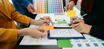 UX developer and ui designer brainstorming about mobile app interface wireframe design with customer breif and color code at office. photo