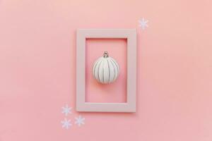 Simply minimal composition winter objects ornament ball in pink frame isolated on pink pastel trendy background photo