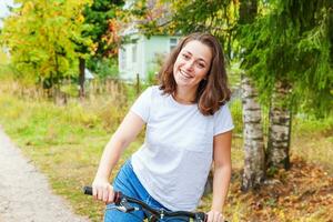 Young woman riding bicycle in summer city park outdoors. Active people. Hipster girl relax and rider bike. Cycling to work at summer day. Bicycle and ecology lifestyle concept. photo