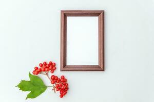 Autumn floral composition. Vertical photo frame mockup viburnum berries on white background. Autumn fall natural plants ecology fresh wallpaper concept. Flat lay top view, copy space