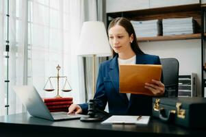 justice and law concept. Female judge in a courtroom  the gavel, working with smart phone and laptop and digital tablet computer on black  table photo