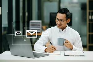 Asian man hands using Laptop, tablet typing on keyboard and surfing the internet with email icon, email marketing concept, send e-mail or newsletter, online working internet network technology. photo