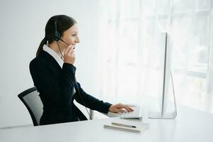 Serious call center operator in wireless headset talking with customer, woman in headphones with microphone consulting client on phone in customer support service in office center photo