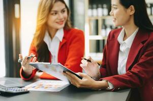 Businesswoman and team analyzing financial statement Finance task. with smart phone and laptop and  tablet. Wealth management concept in office photo