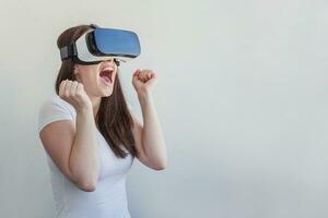 Smile young woman wearing using virtual reality VR glasses helmet headset on white background. Smartphone using with virtual reality goggles. Technology, simulation, hi-tech, videogame concept. photo
