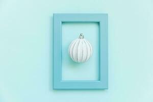 Simply minimal composition winter objects ornament ball in blue frame isolated on blue pastel trendy background photo