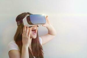 Smile young woman wearing using virtual reality VR glasses helmet headset on white background. Smartphone using with virtual reality goggles. Technology, simulation, hi-tech, videogame concept. photo