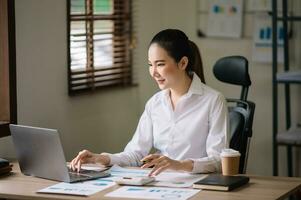 Asian businesswoman working in the office with working notepad, tablet and laptop documents photo