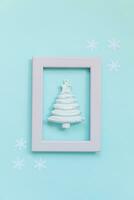 Simply minimal composition winter objects ornament fir tree in pink frame isolated on blue pastel trendy background photo