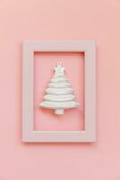 Simply minimal composition winter objects ornament fir tree in pink frame isolated on pink pastel trendy background photo