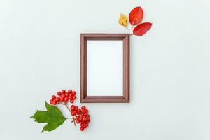 Autumn floral composition. Vertical photo frame mockup viburnum berries colorful leaves on white background. Fall natural plants ecology fresh wallpaper concept. Flat lay top view, copy space
