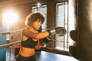 mujer yo defensa niña fuerza. africano americano mujer combatiente formación puñetazos en boxeo anillo. sano fuerte niña puñetazos boxeo bolsa. formación día en boxeo gimnasia. fuerza ajuste cuerpo rutina de ejercicio capacitación. foto