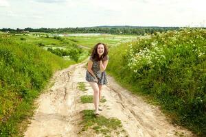 belleza niña al aire libre disfrutando naturaleza. hermosa mujer saltando en verano campo con floreciente salvaje flores, Dom ligero. gratis contento mujer. foto