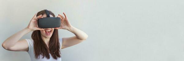 sonrisa joven mujer vistiendo utilizando virtual realidad vr lentes casco auriculares en blanco antecedentes. teléfono inteligente utilizando con virtual realidad gafas de protección. tecnología, simulación, de alta tecnología, videojuego concepto. bandera foto