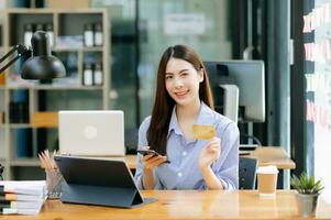 Asian Woman using smart phone for mobile payments online shopping,omni channel,sitting on table,virtual icons graphics interface screen in morning light photo