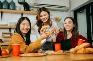 Group of friends making fun at home party.They sitting on desk in living room and eating pizza. happy photo