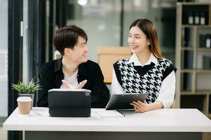 Two Asian business workers talking on the smartphone and using laptop at the modern office. photo