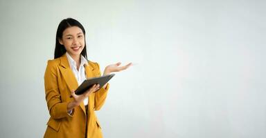 Portrait photo of young beautiful Asian woman feeling happy and holding smart phone, tablet and laptop with black empty screen on white background product presenting concept.