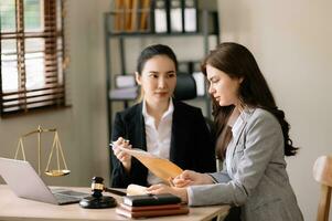 udge gavel with scales of justice, Business and lawyer or counselor consulting and discussing contract papers with laptop and tablet at law firm in office. photo