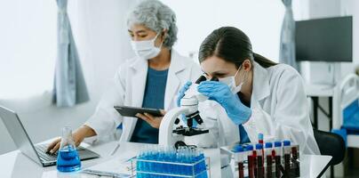 Two scientist or medical technician working, having a medical discuss meeting with an Asian senior female scientist supervisor in the laboratory with online reading, test samples and innovation photo