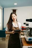 Startup successful small business owner sme woman stand with tablet  in cafe. woman barista cafe owner. photo