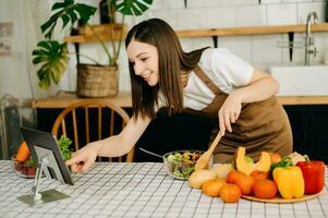 Young woman video blogger cooking at the kitchen and filming healthy food concept at home photo