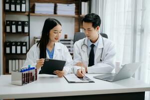 Medical technology network team meeting concept. Asian Doctor hand working with smart phone modern digital tablet and laptop computer with graphics chart interface, photo