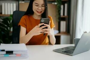 Woman using smart phone for mobile payments online shopping, omni channel, sitting on table, virtual icons graphics interface screen photo