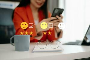 Customer service evaluation concept. Businesswoman pressing face smile emoticon show on virtual screen at tablet and smartphone in office photo