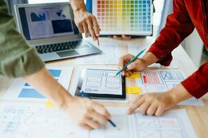 UX developer and ui designer brainstorming about mobile app interface wireframe design with customer breif and color code at office. photo