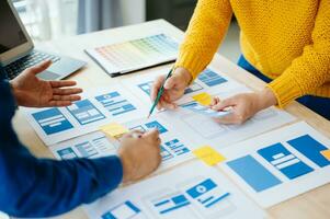 UX developer and ui designer brainstorming about mobile app interface wireframe design with customer breif and color code at office. photo