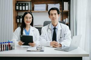 Medical technology network team meeting concept. Asian Doctor hand working with smart phone modern digital tablet and laptop computer with graphics chart interface, photo