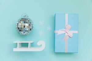 simplemente mínimo composición invierno objetos ornamento pelota trineo regalo caja aislado en azul pastel de moda antecedentes foto