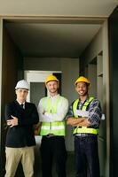 Architect caucasian man working with colleagues mixed race in the construction site. Architecture engineering on big project. Building in construction process interior. look at camera photo