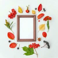 Autumn floral composition. Vertical frame mockup chokeberry rowan berries colorful leaves dogrose flowers on white background. Fall natural plants ecology concept. Flat lay top view, copy space photo