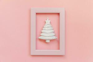 Simply minimal composition winter objects ornament fir tree in pink frame isolated on pink pastel trendy background photo