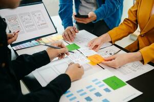 UX developer and ui designer brainstorming about mobile app interface wireframe design with customer breif and color code at office. photo