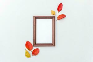 Autumn floral composition. Vertical photo frame mockup and colorful leaves on white background. Fall natural plants ecology fresh wallpaper concept. Flat lay top view, copy space