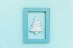 Simply minimal composition winter object ornament fir tree in blue frame isolated on blue pastel trendy background photo