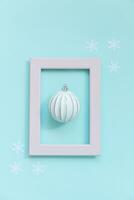 Simply minimal composition winter objects ornament ball in pink frame isolated on blue pastel trendy background photo
